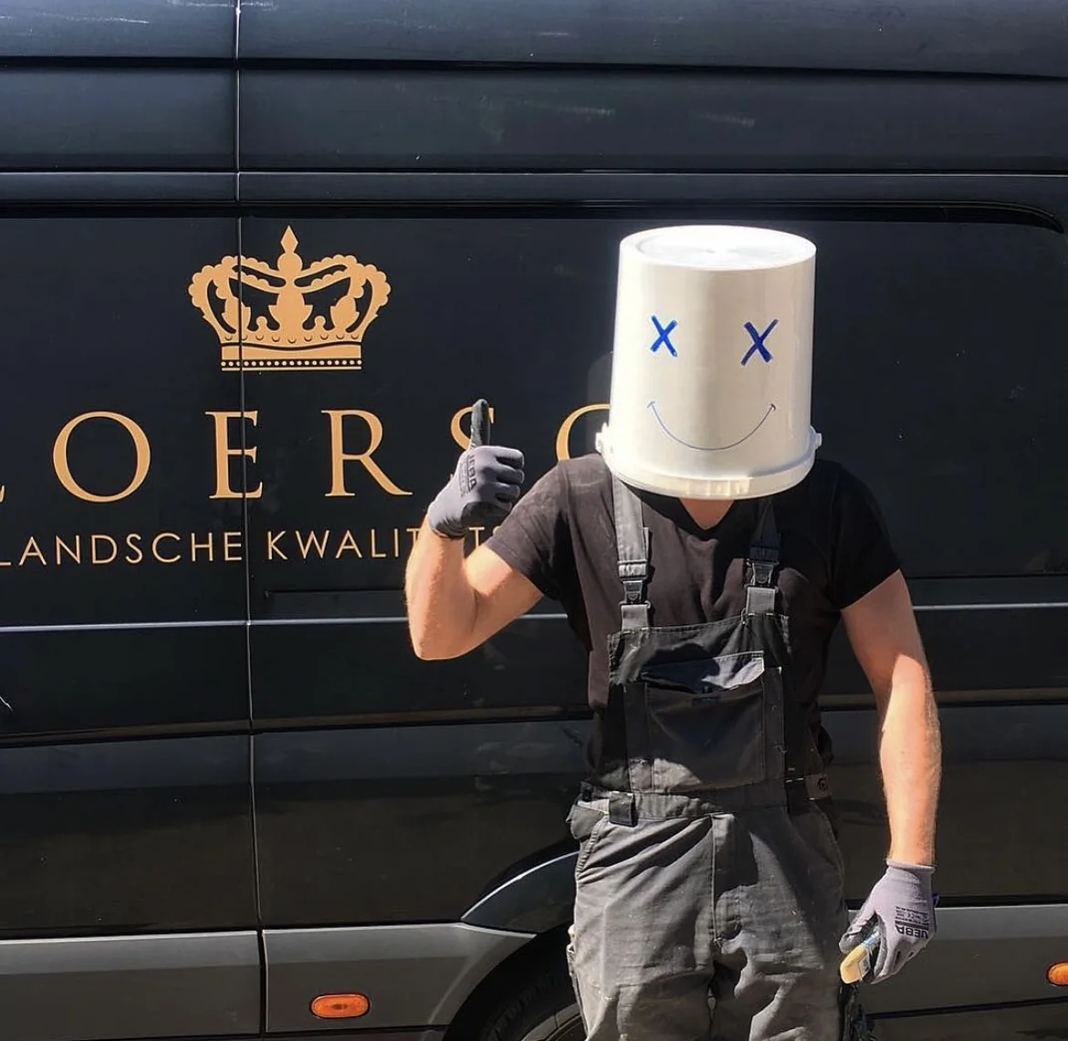 Michal, project manager at Vloersch, with a bucket on his head in front of the Vloersch van