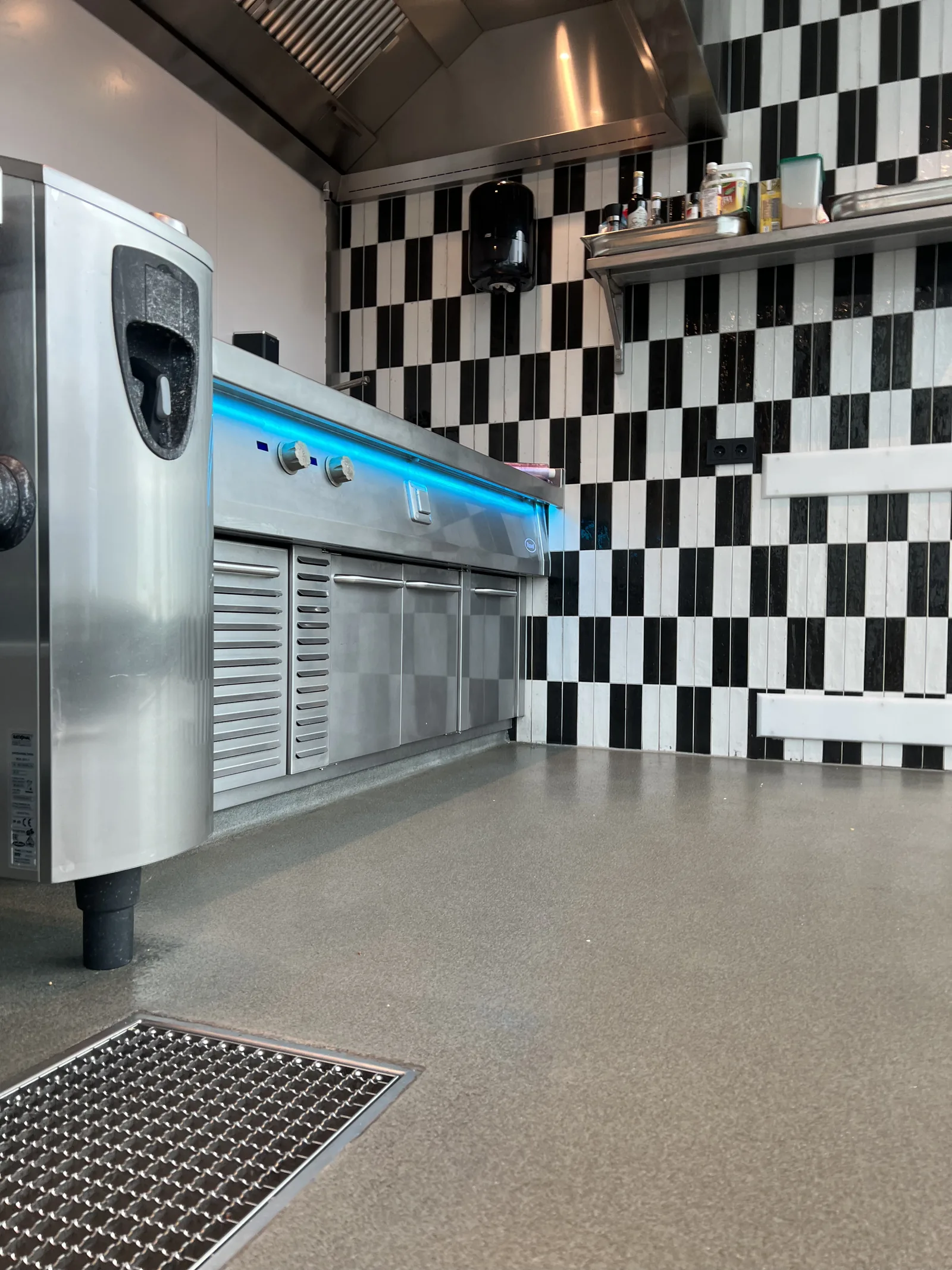 Completec QCF quartz floor in a commercial kitchen with stainless steel cooking equipment and a chequered tiled wall